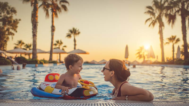 Mãe e filho na piscina ao pôr do sol